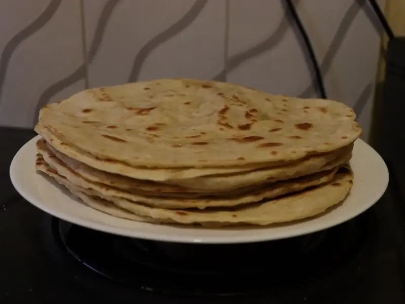 A cooked chapati, puffed and marked with brown spots.