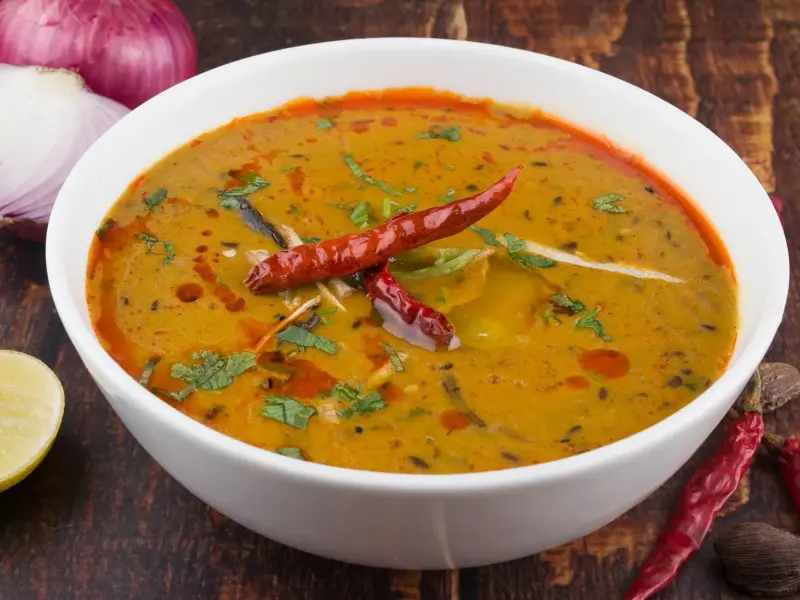 A bowl of dal tadka with a tempering of cumin and chilli poured over the surface.