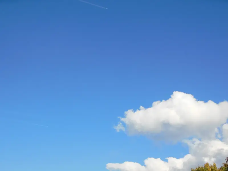 A deep blue daytime sky with scattered white cumulus clouds.
