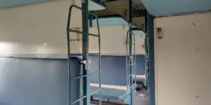 The interior of an Indian Railways sleeper coach with berths on either side of the aisle.