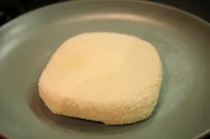 A block of fresh homemade paneer on a board.