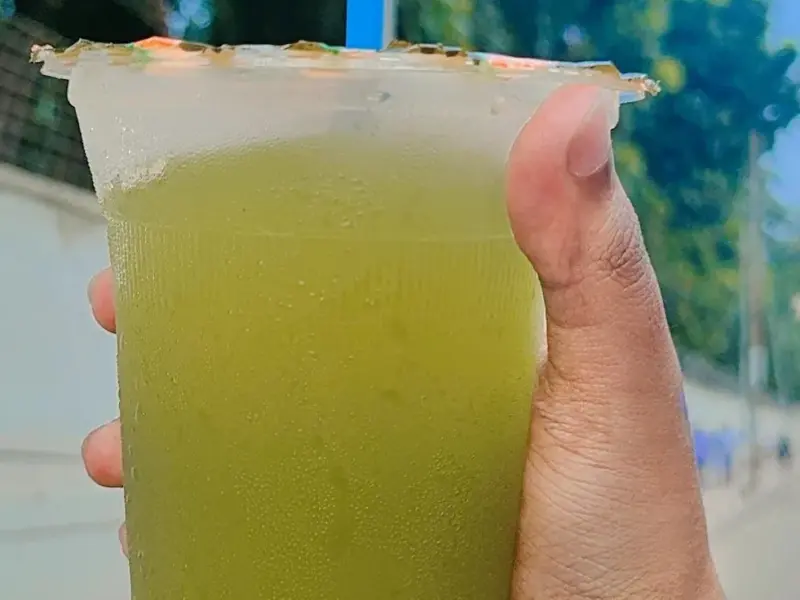 A tall glass of mint lemonade with ice and fresh mint leaves.
