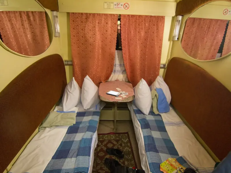 The interior of a railway sleeping car with made-up berths.