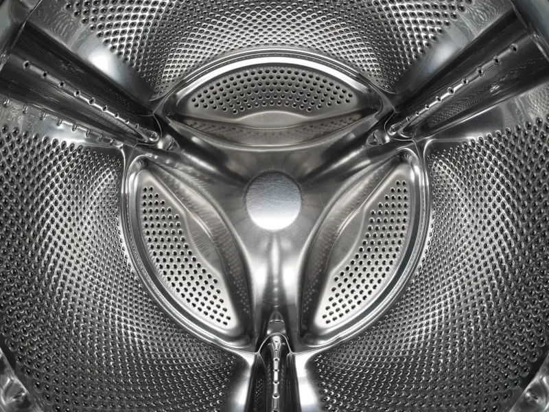 The stainless steel drum of a front-loading washing machine, seen through the open door.