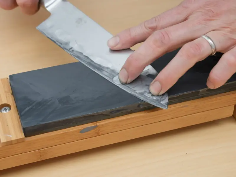 A kitchen knife being drawn across a wet whetstone.