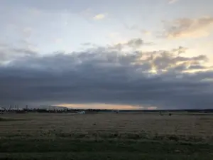 A bank of low cloud approaching across open country ahead of a front.