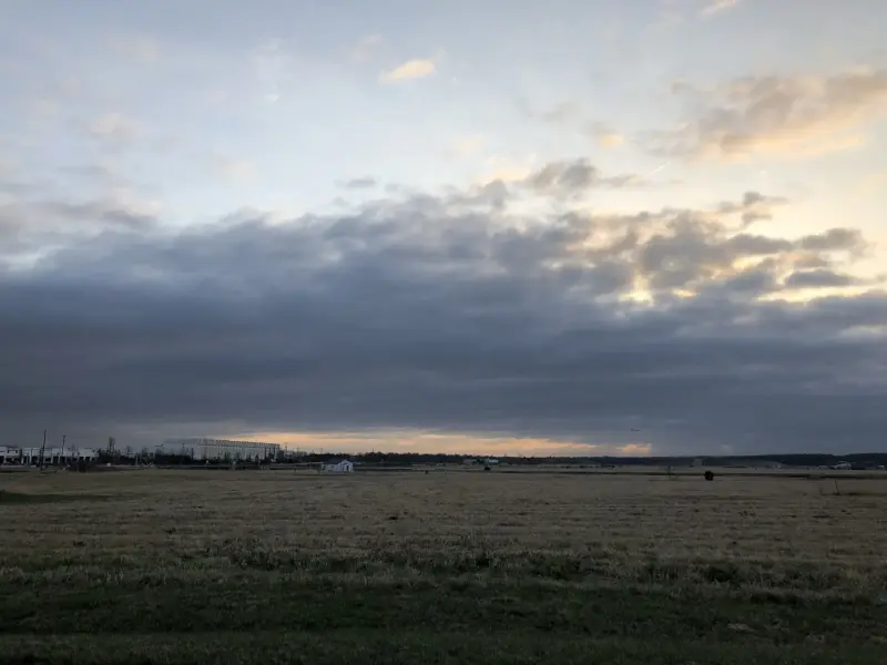 A bank of low cloud approaching across open country ahead of a front.